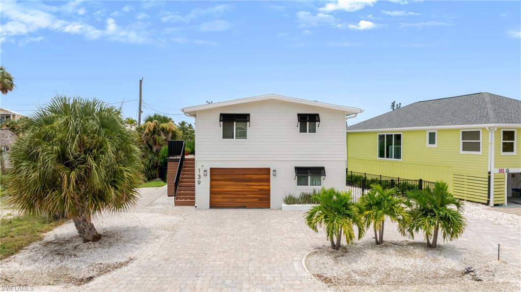 White exterior with horizontal siding, wood-finish garage door, and black window awnings