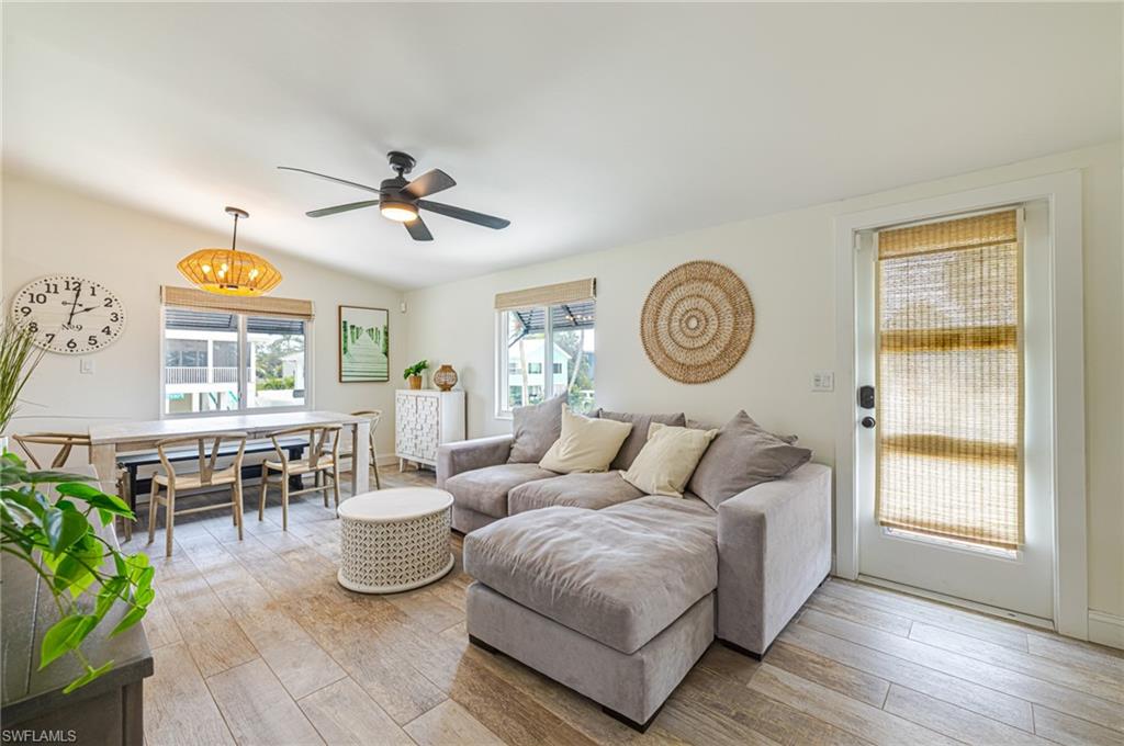 Bright interior space featuring wood-finish flooring, a vaulted ceiling, and a ceiling fan with integrated lighting