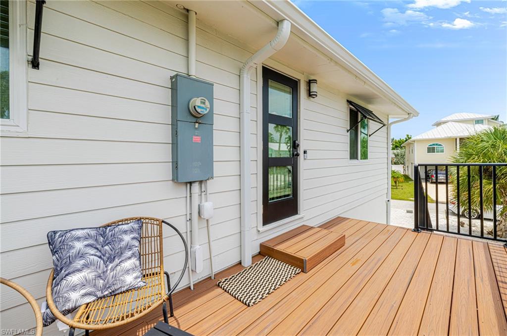 Outdoor deck featuring wood-finish flooring, a black metal railing, and a black paneled door with glass inserts
