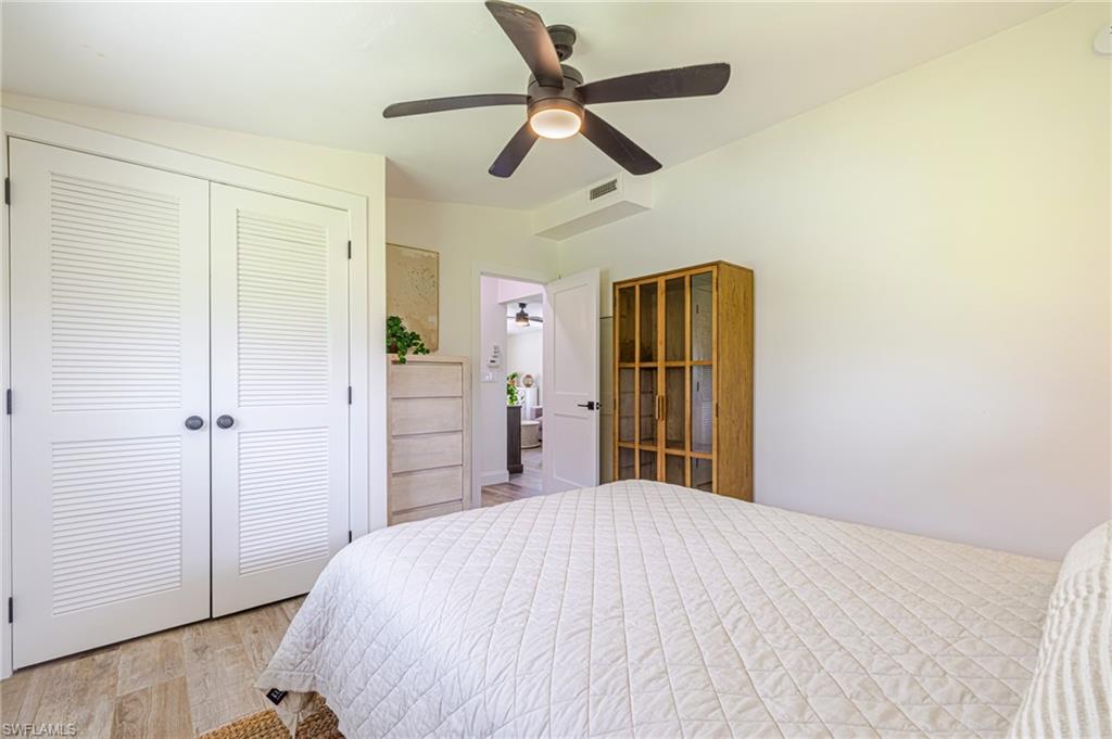 White louvered bifold doors, wood-finish flooring, and a ceiling fan with integrated lighting