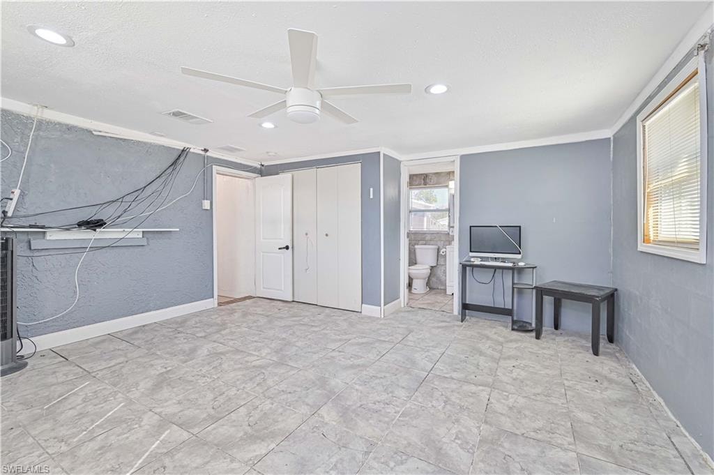 Bedroom with a closet, a ceiling fan, ensuite bath, recessed lighting, and a textured wall
