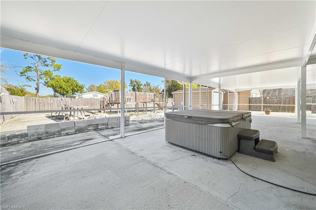 Fenced backyard featuring a patio, a storage unit, and a hot tub