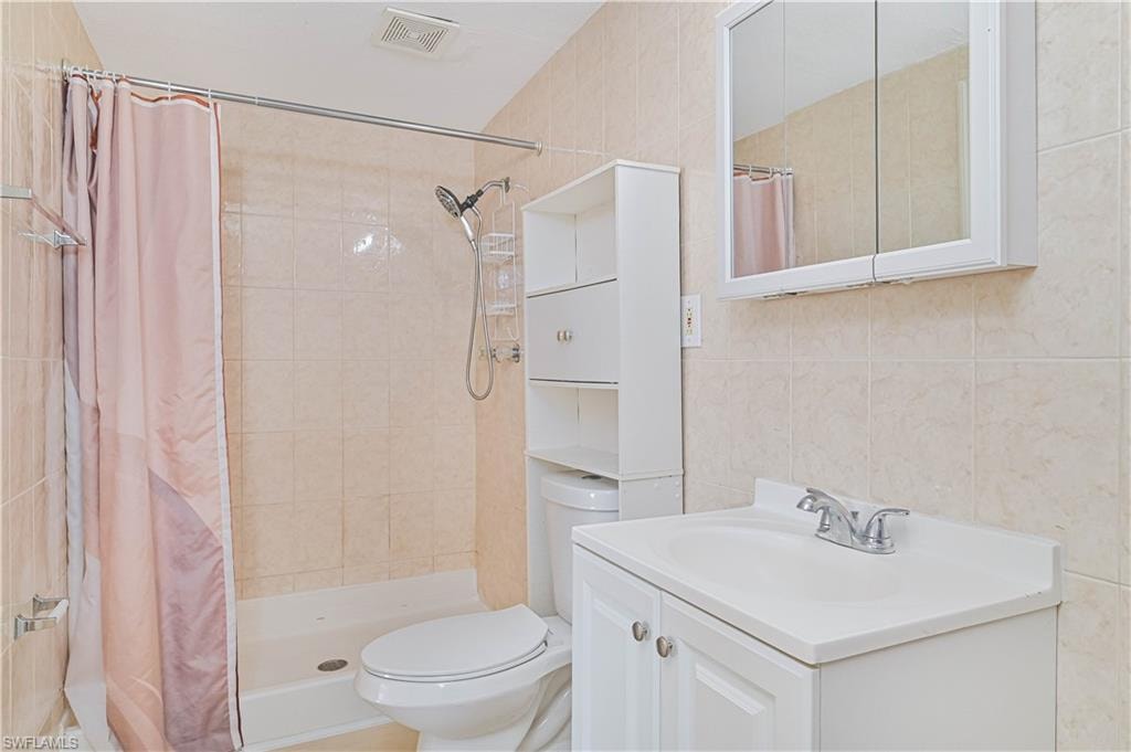 Full bathroom with a shower stall, vanity, and tile walls