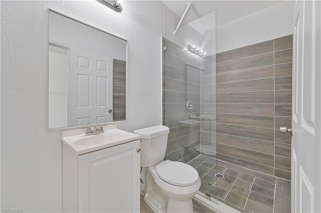 Bathroom with a textured wall, tiled shower, and vanity