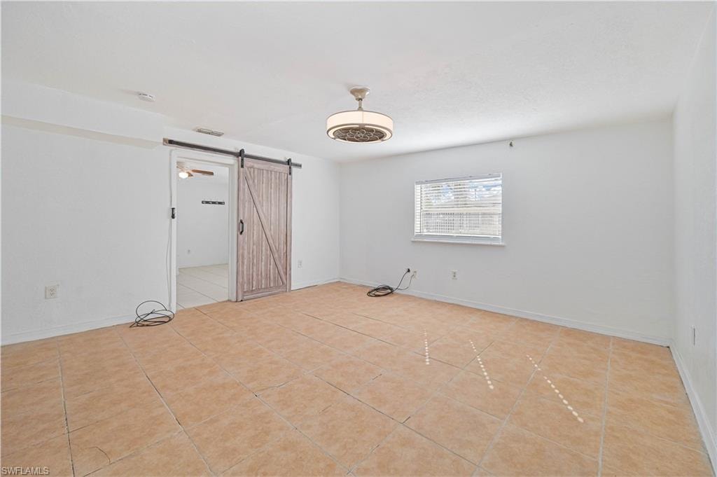 Unfurnished room featuring a barn door and light tile patterned flooring