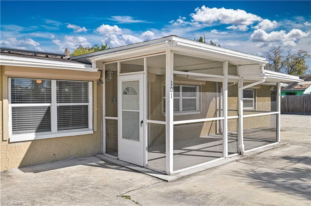 View of exterior entry with a sunroom and stucco siding