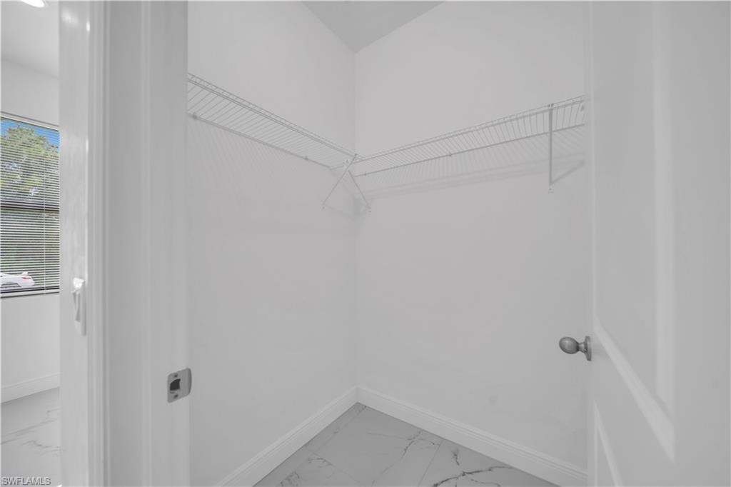 Walk-in closet featuring wire shelving, white painted walls, white baseboards, and patterned tile flooring