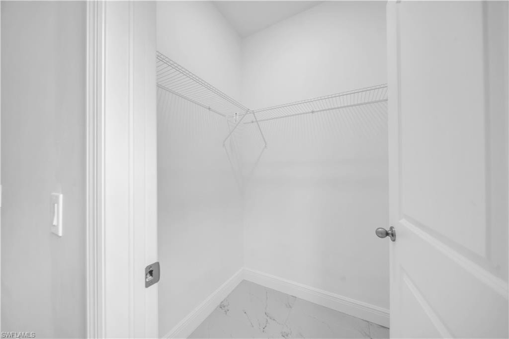 Spacious closet featuring white wire shelving and a white marble-look floor