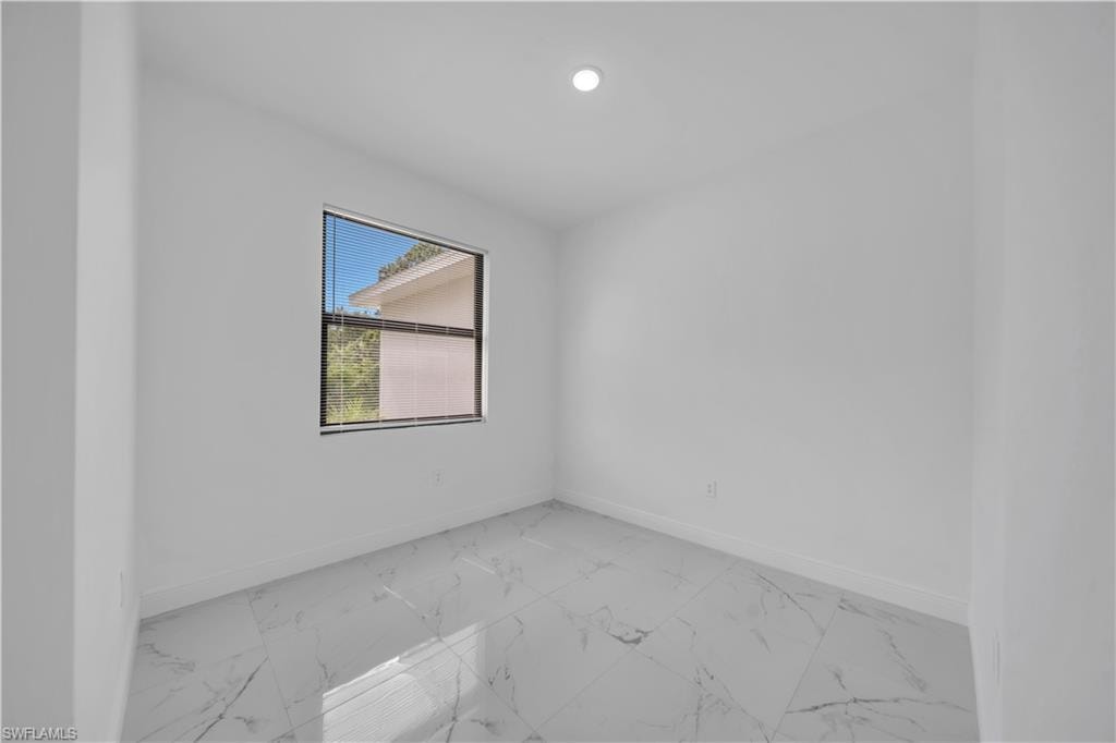 Bright interior space featuring white walls and white marble-look tile flooring