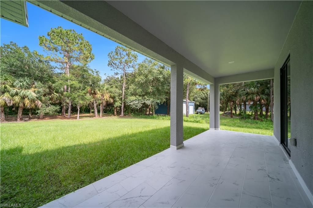 Spacious covered patio featuring large format tile flooring and multiple support columns