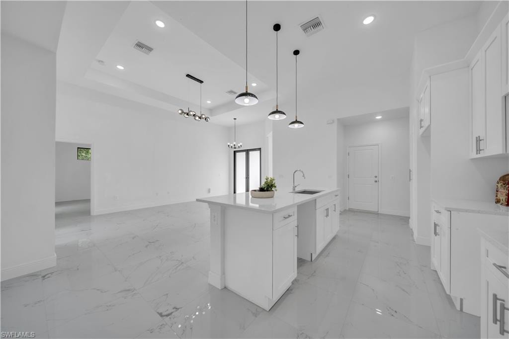 Open-concept kitchen and living area featuring a central island, white cabinetry, and large format tile flooring
