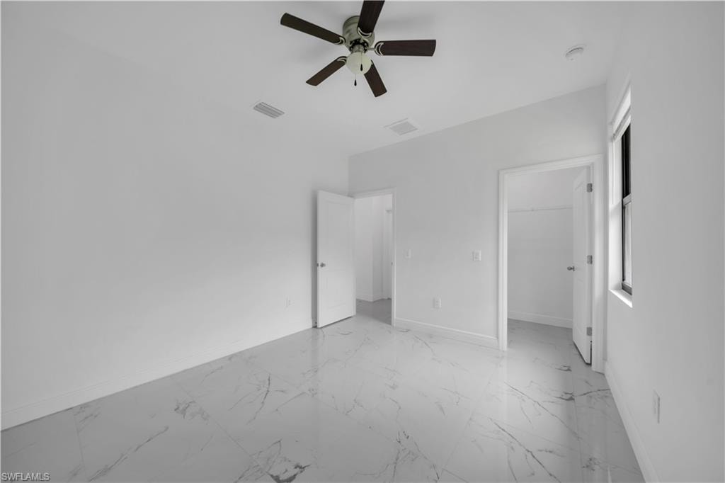 Spacious room featuring large format tile flooring, a ceiling fan, and white baseboards
