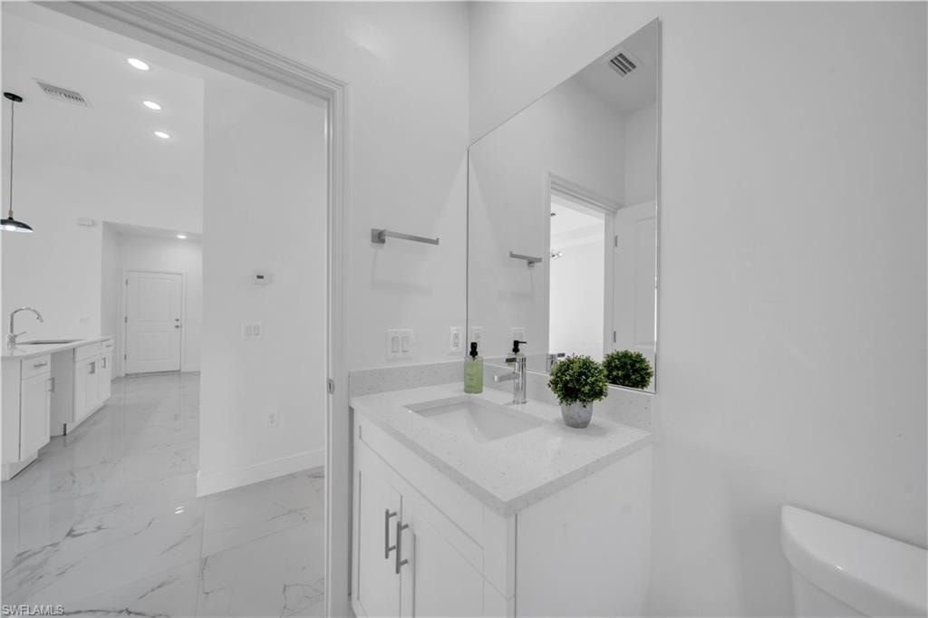 Bathroom featuring a vanity with a white countertop and rectangular undermount sink, a large wall-mounted mirror, and tile flooring