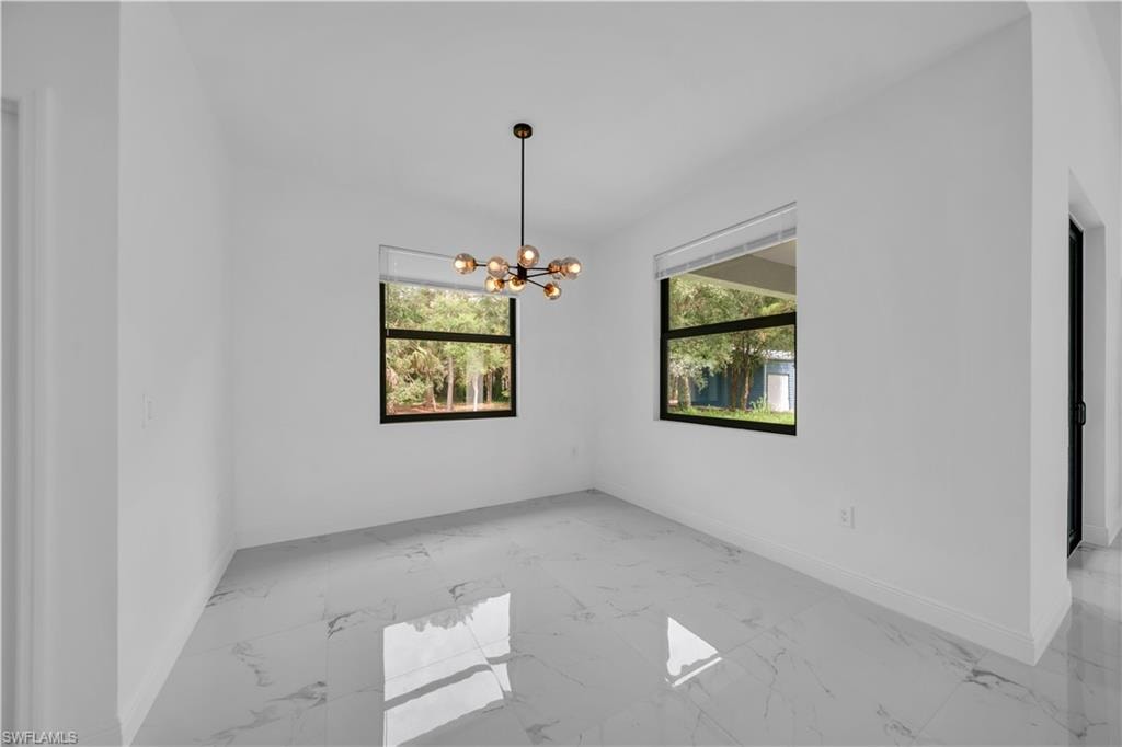 Spacious room featuring white walls, large windows, a contemporary chandelier, and polished tile flooring