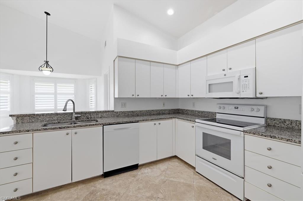 Kitchen featuring white cabinetry, speckled countertops, stainless steel sink, and light-toned tile flooring