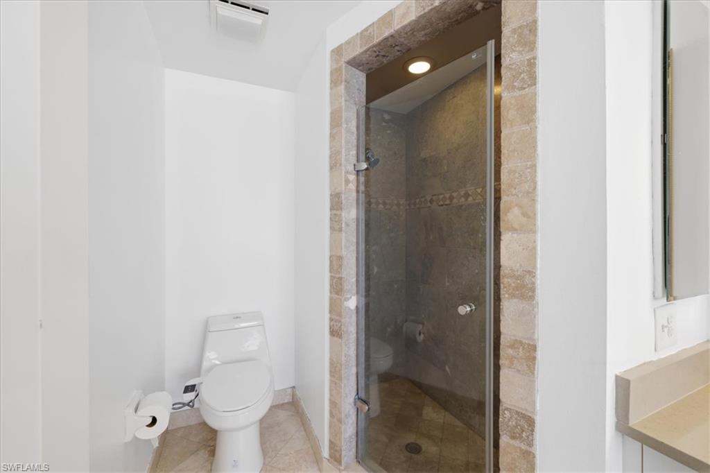Enclosed shower with stone tile surround and glass door
