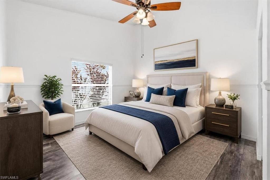 Spacious room featuring vaulted ceilings, a prominent window with horizontal blinds, wood-finish flooring, and crown molding