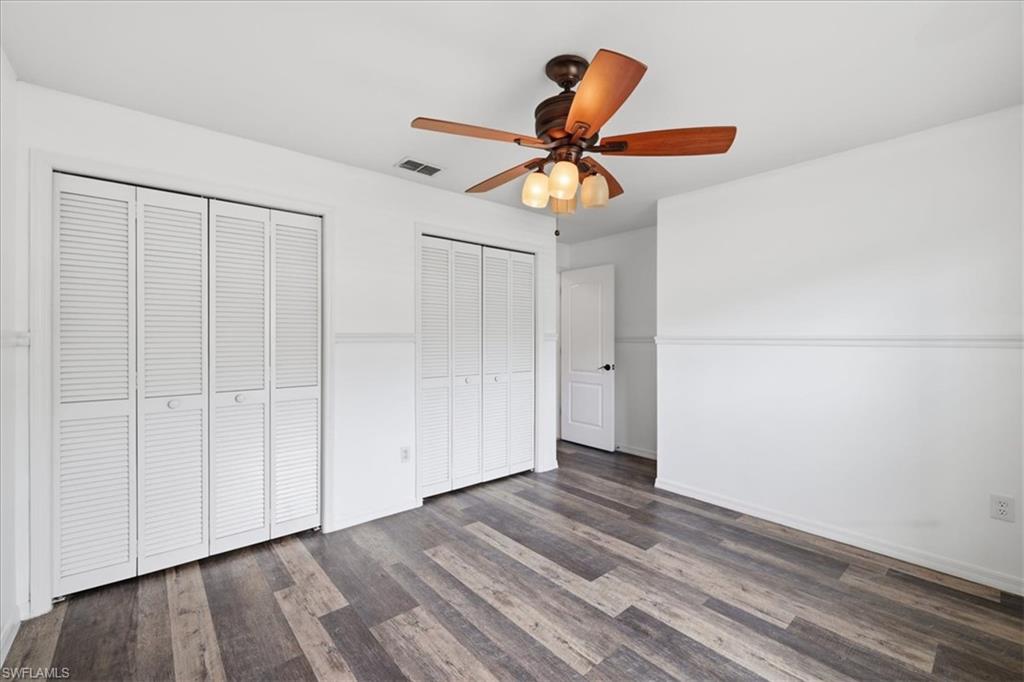 Room featuring wood-finish flooring, white walls with wainscoting, and a ceiling fan with integrated lighting