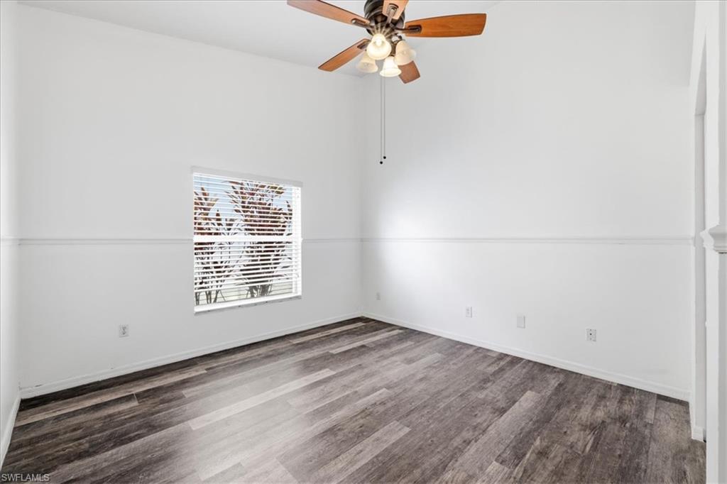 Interior room with wood-finish flooring, white walls, and a vaulted ceiling