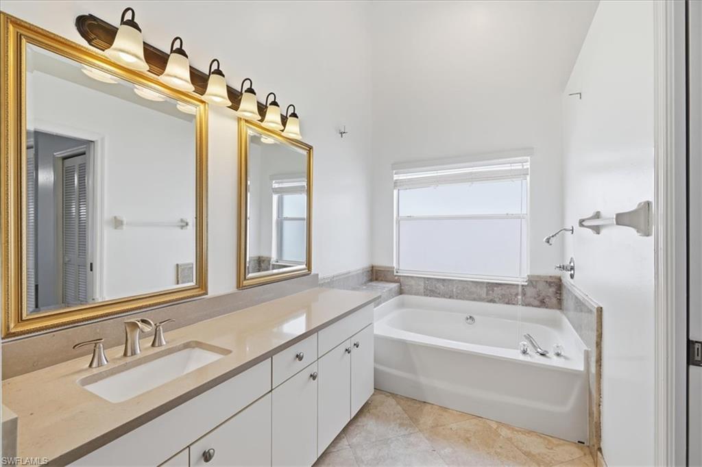 Bathroom featuring a double vanity with integrated sinks, brushed nickel fixtures, and a spacious soaking tub