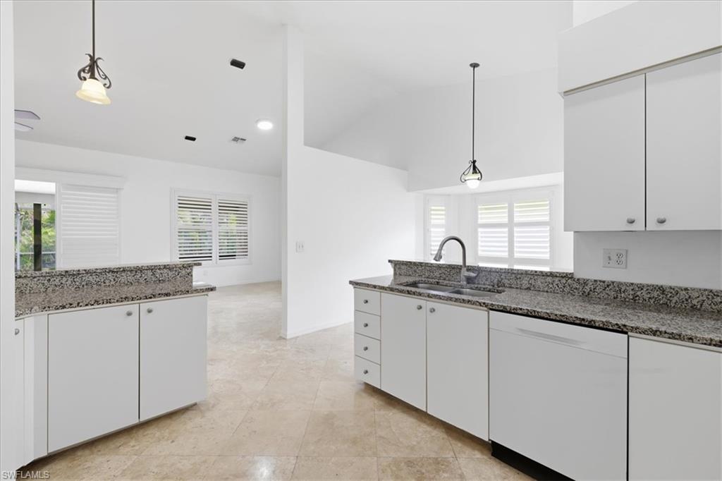 Kitchen featuring white cabinetry, granite countertops, tile flooring, pendant lighting, and a built-in dishwasher