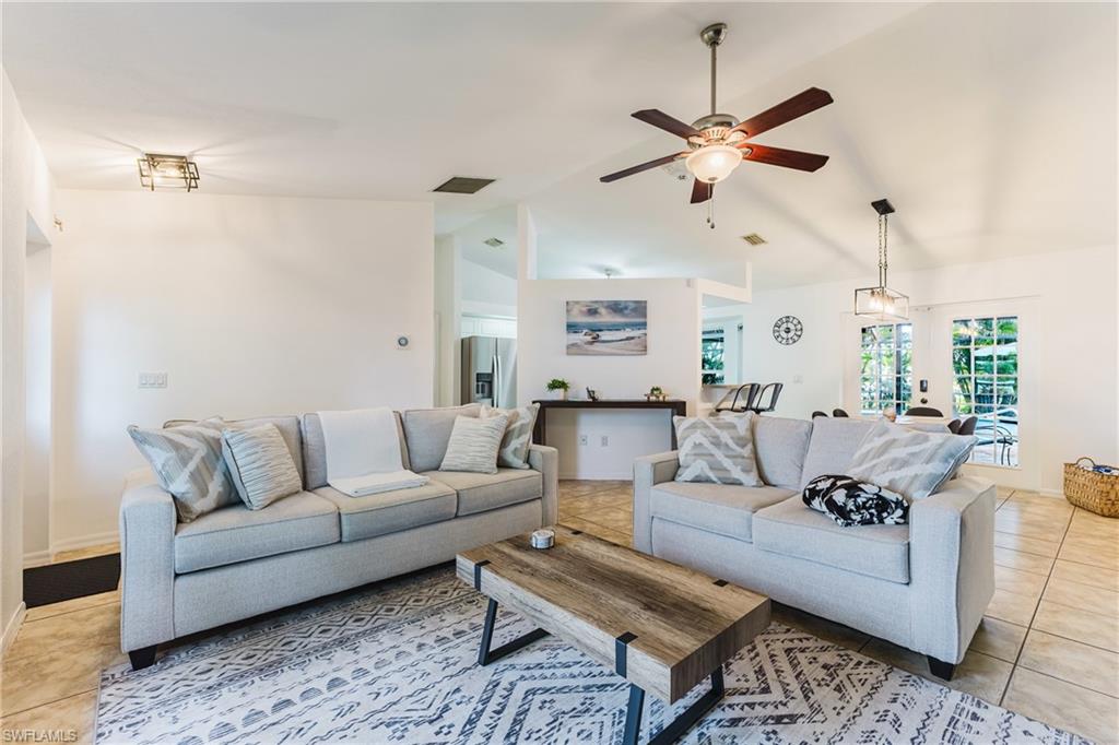 Spacious living area featuring vaulted ceilings, tile flooring, and a ceiling fan
