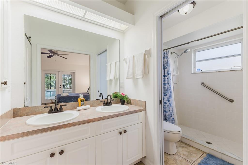 Bathroom featuring a dual vanity with a tan countertop, white cabinetry, and bronze-finish hardware