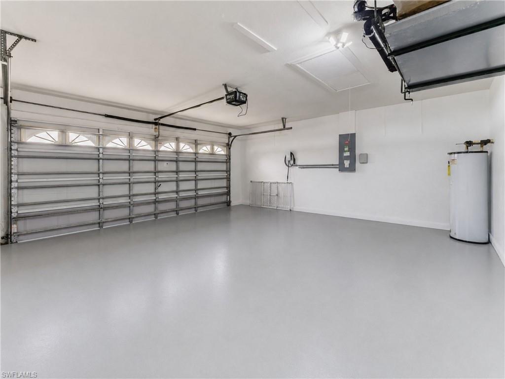 Spacious garage featuring a durable epoxy floor, an automatic garage door with upper window detailing, and integrated overhead lighting