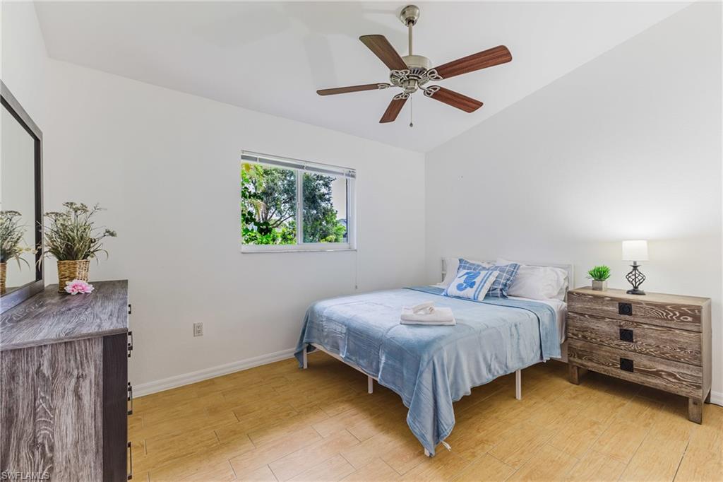 Bright room featuring wood plank tile flooring, a window offering exterior views, a ceiling fan with integrated lighting, and white walls