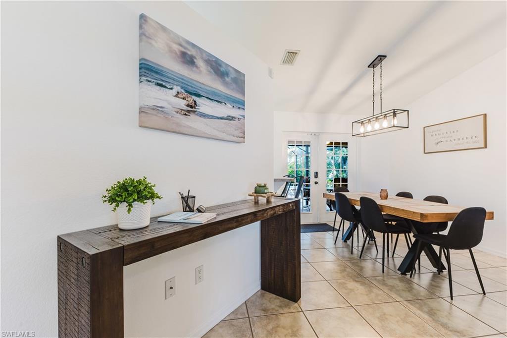 Open dining area featuring neutral tile flooring, a vaulted ceiling, and an industrial-style linear chandelier