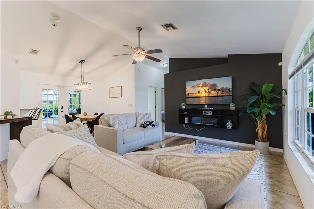 Vaulted ceilings enhance this open concept living area featuring a dark accent wall with a built-in media console and electric fireplace