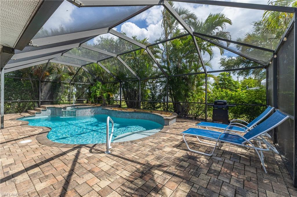 Screened pool enclosure featuring a freeform pool with integrated spa and waterfall