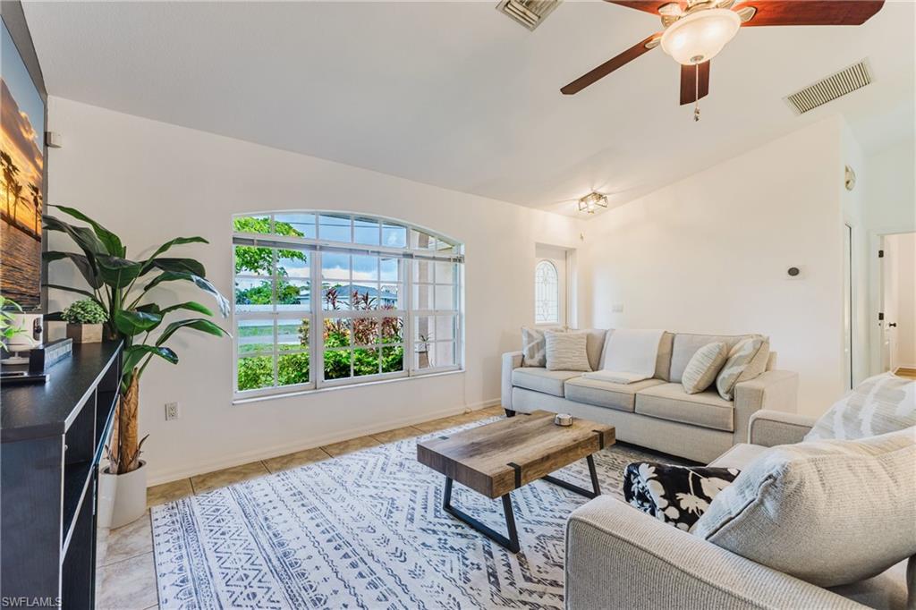 Living area with an arched window, vaulted ceiling, and tile flooring