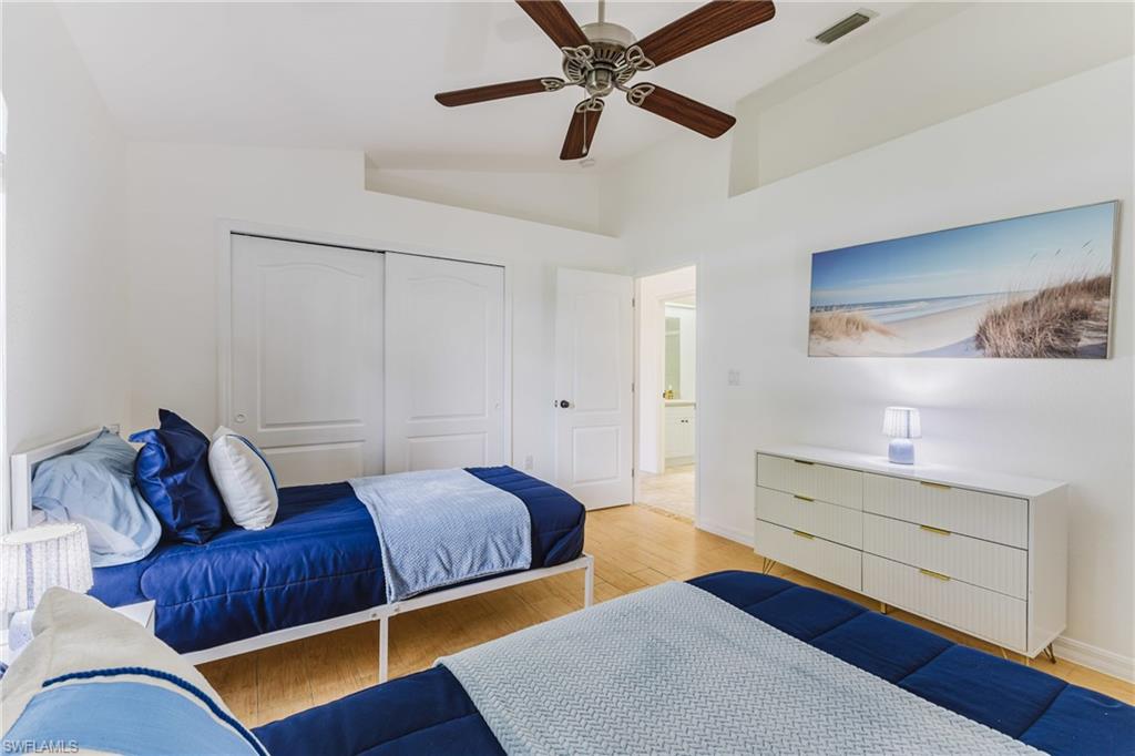 Vaulted ceiling room featuring light-toned wood plank tile flooring, a ceiling fan, and sliding closet doors