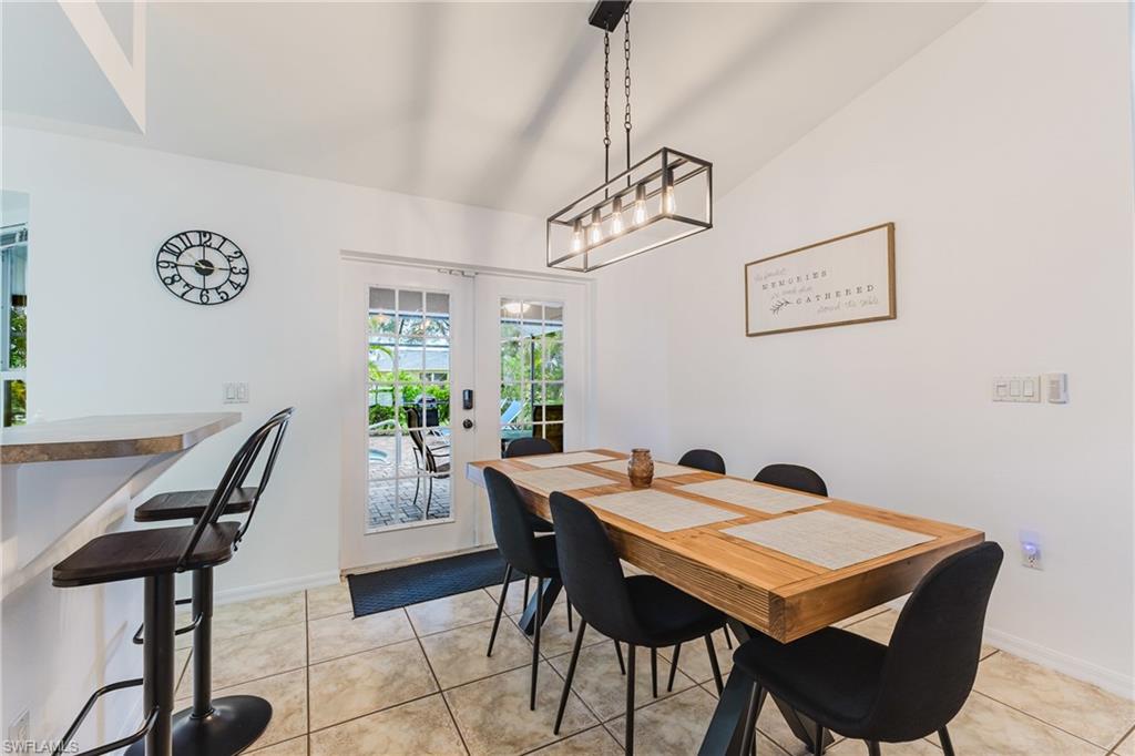 Dining area with vaulted ceiling, white walls, and tiled flooring