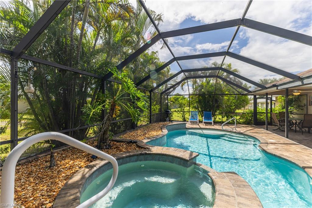 Screened outdoor oasis featuring a freeform swimming pool and integrated spa