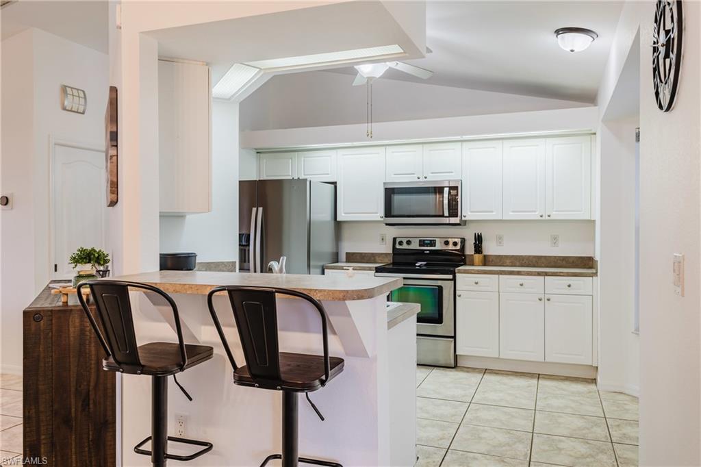 Kitchen featuring white cabinetry, stainless steel appliances, and a breakfast bar with a neutral countertop