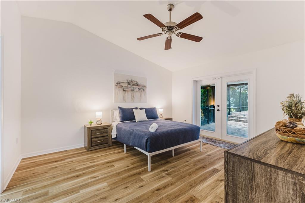 Vaulted ceiling with an overhead fan, wood plank LVP, and white walls