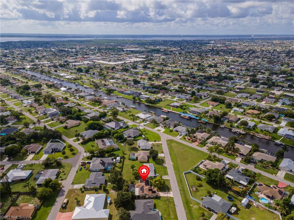 Aerial depiction of a residential area featuring multiple waterways, numerous properties with individual lots, and a distant body of water