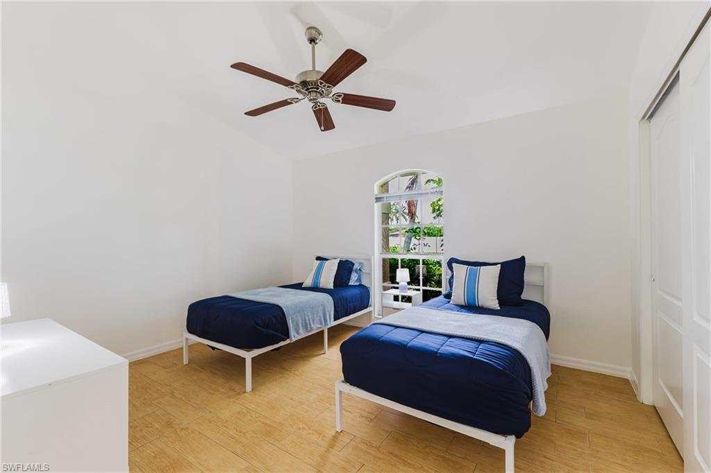 Room featuring wood plank tile flooring, a ceiling fan, an arched window, and a white sliding closet door