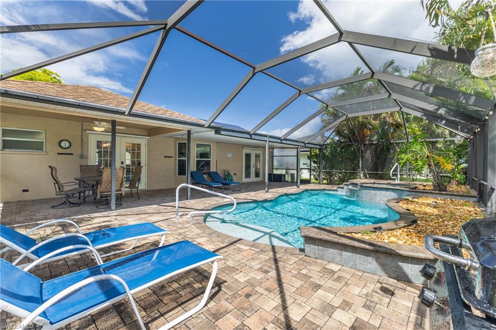 Screened lanai featuring a swimming pool, integrated spa, and extensive paver decking