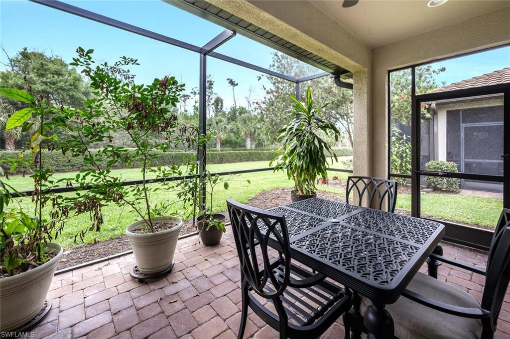 Screened lanai featuring brick paver flooring, a textured ceiling, and expansive views of the landscaped yard