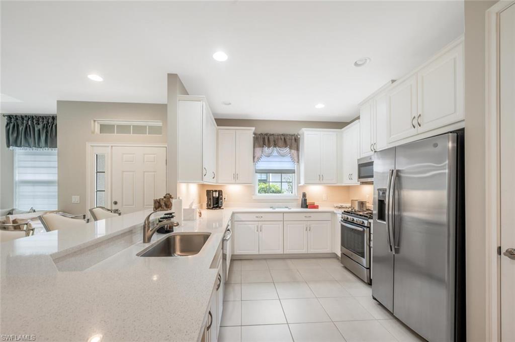 Modern kitchen featuring white cabinetry, light-toned countertops, stainless steel appliances, and recessed lighting