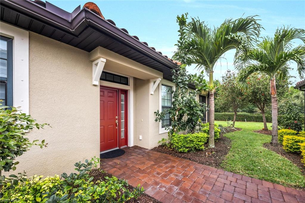 Stucco exterior with a red front door, terracotta roof tiles, and a brick paver walkway