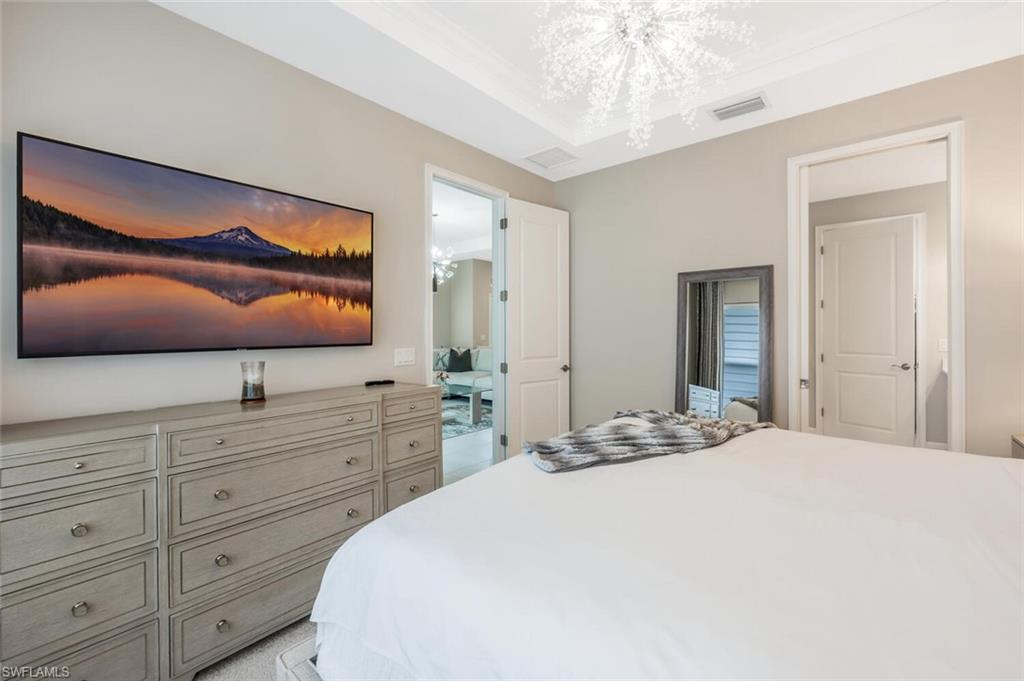Recessed ceiling with crown molding, a modern chandelier, and neutral wall tones