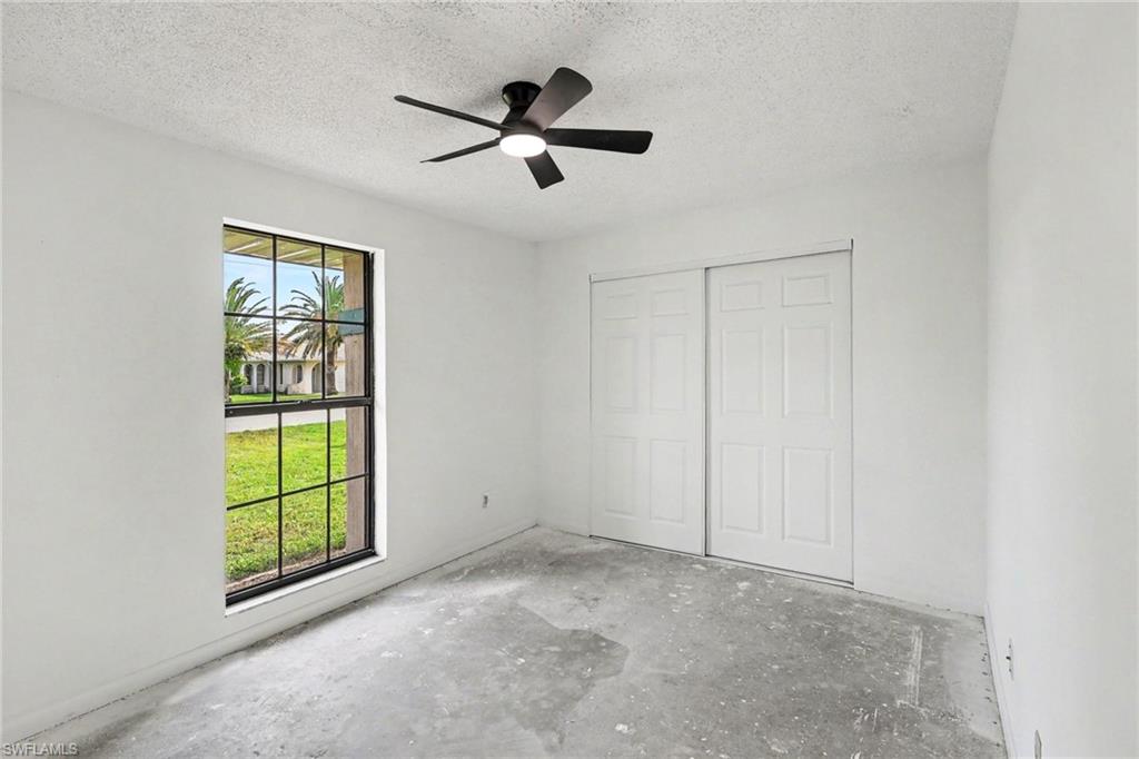 Bright interior space featuring a multi-pane window, white walls, and a ceiling-mounted fan with integrated lighting