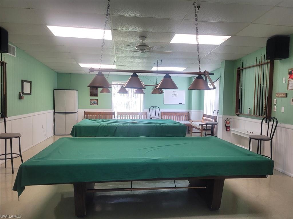 Rec room featuring a wainscoted wall, ceiling fan, a paneled ceiling, and pool table