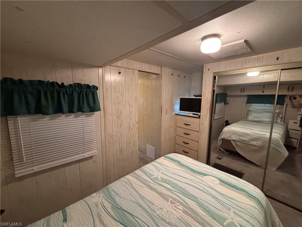 Light-colored wood-paneled walls with an integrated wardrobe featuring mirrored sliding doors