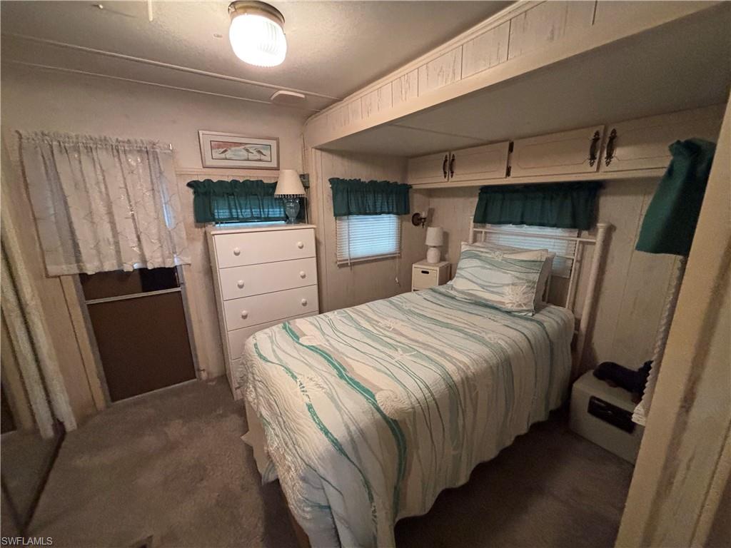 Built-in overhead cabinetry, wall-mounted light fixture, and window with blinds