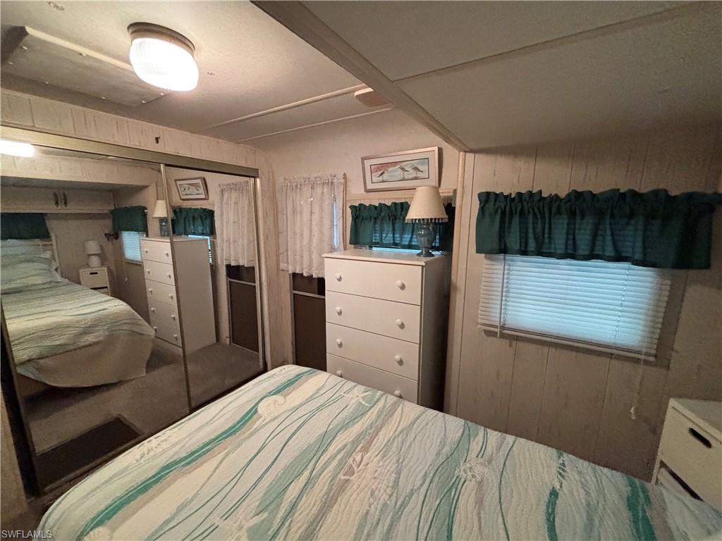 Mirrored sliding closet doors, wall-mounted light fixture, and window with blinds